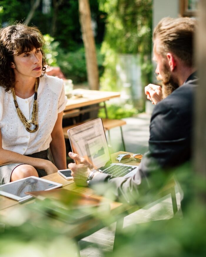 Twee mensen in gesprek aan een tafel buiten