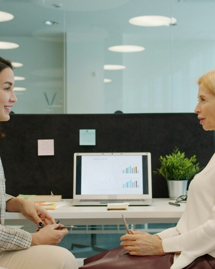 Twee vrouwen in gesprek aan een bureau op kantoor